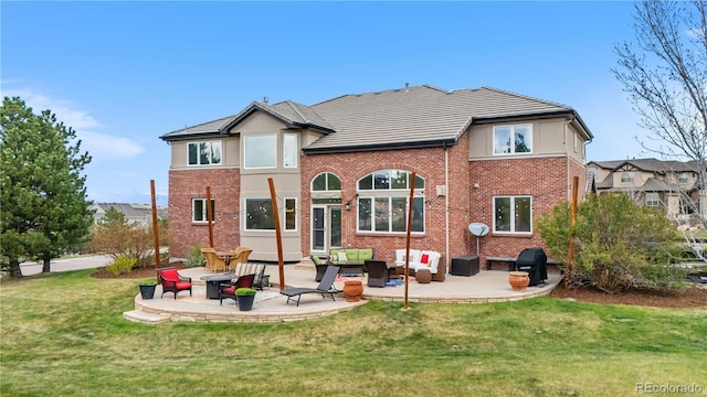 rear view of property featuring a patio, an outdoor hangout area, a lawn, and brick siding