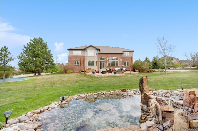 rear view of house featuring a yard, a patio, and brick siding