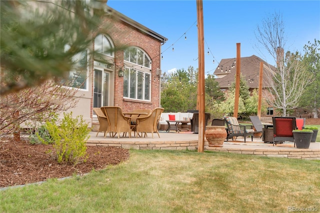 back of property featuring brick siding, an outdoor living space, a yard, and a patio