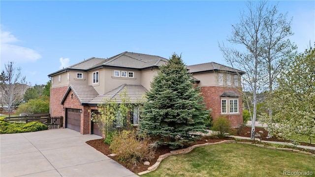 traditional home featuring a front yard, brick siding, a tiled roof, an attached garage, and driveway