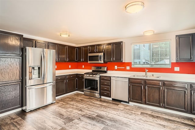 8057 Bryant St, Westminster, CO 80031 - kitchen with appliances with stainless steel finishes, light countertops, dark brown cabinetry, and light wood-style flooring