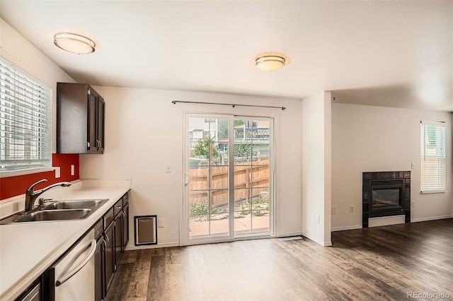 8057 Bryant St, Westminster, CO 80031 - kitchen featuring wood finished floors, a tile fireplace, dishwasher, light countertops, and dark brown cabinets