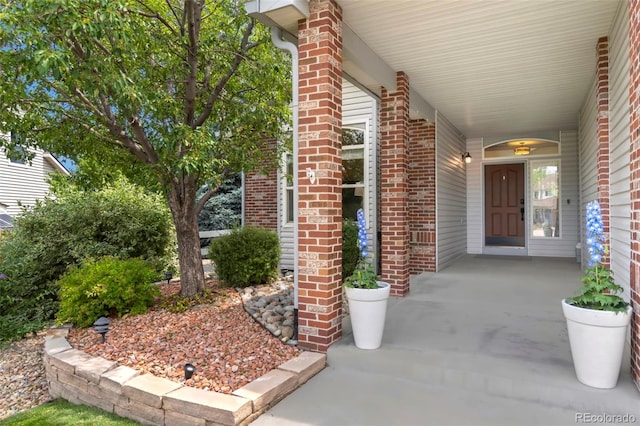 property entrance featuring brick siding and covered porch