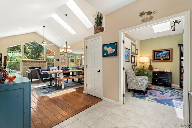 interior space featuring a stone fireplace, vaulted ceiling with skylight, light tile patterned flooring, and a healthy amount of sunlight