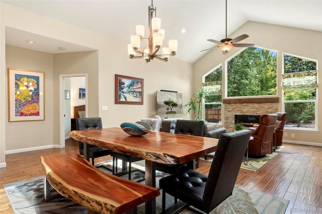 dining space with baseboards, lofted ceiling, a fireplace, and light wood finished floors