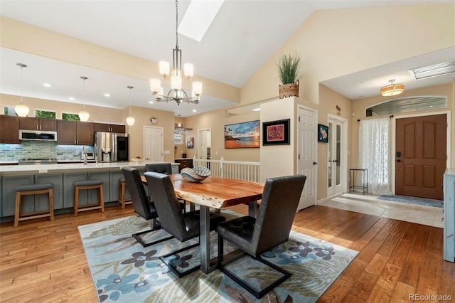 dining space featuring visible vents, an inviting chandelier, high vaulted ceiling, and light wood-style floors