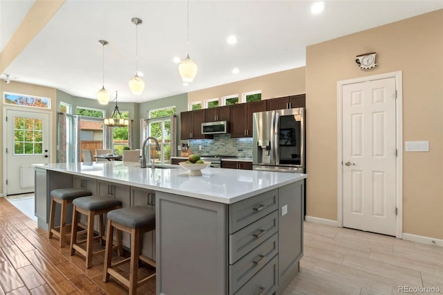 kitchen featuring a breakfast bar, a sink, tasteful backsplash, stainless steel appliances, and light countertops