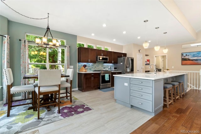 kitchen featuring a sink, appliances with stainless steel finishes, light wood finished floors, decorative backsplash, and light countertops