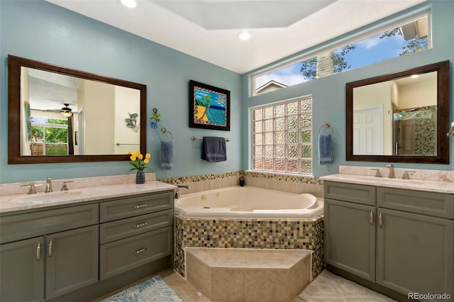 full bathroom featuring a sink, a stall shower, two vanities, and a bath