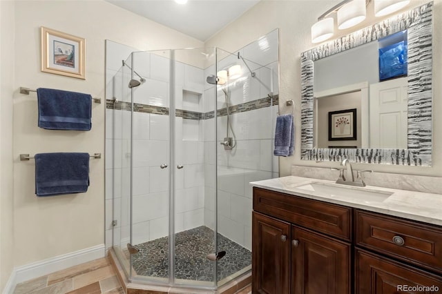 bathroom featuring a shower stall, vanity, and baseboards