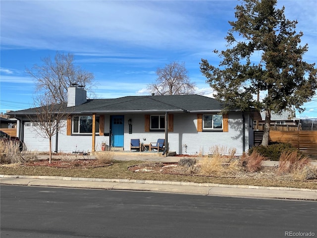 ranch-style home with a garage, covered porch, brick siding, fence, and a chimney