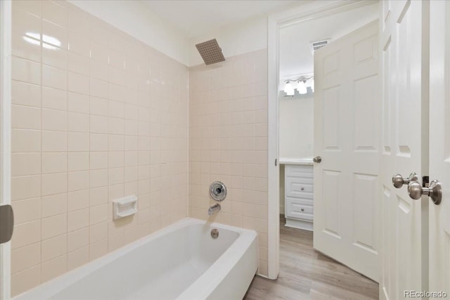 bathroom featuring wood finished floors and washtub / shower combination