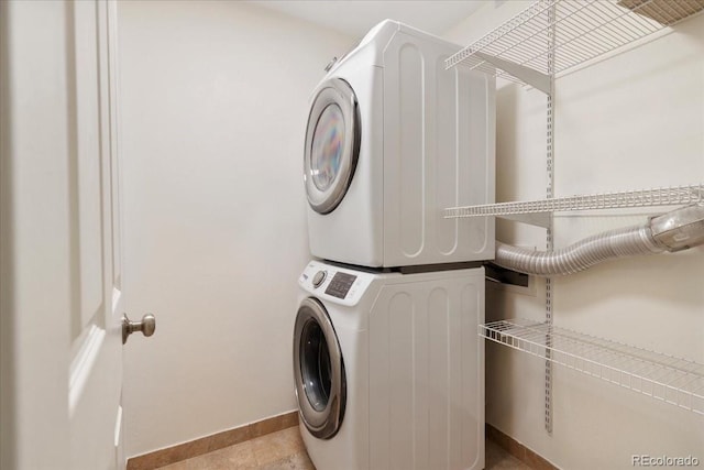 laundry room featuring stacked washer / dryer and baseboards