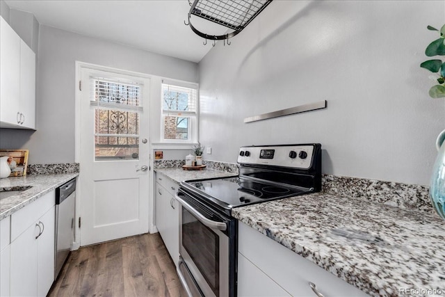 kitchen with sink, white cabinetry, hardwood / wood-style floors, stainless steel appliances, and light stone countertops