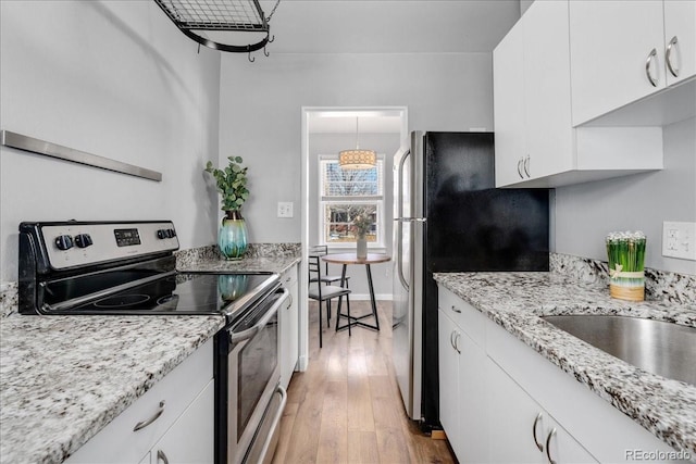 kitchen featuring sink, light hardwood / wood-style flooring, white cabinetry, stainless steel appliances, and light stone counters