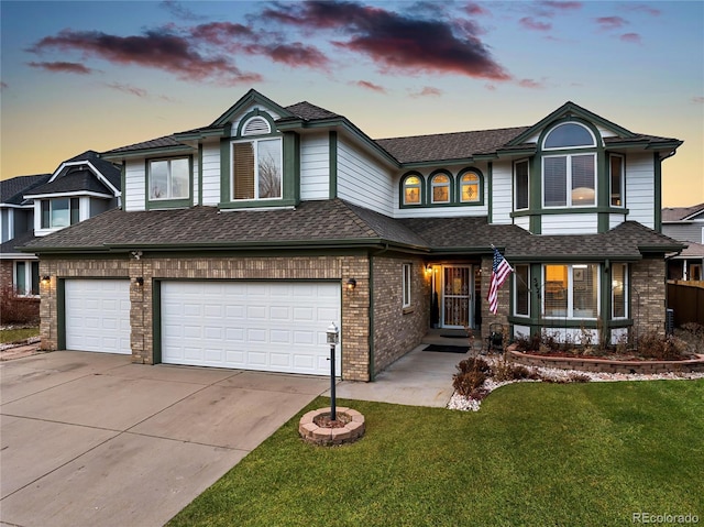 view of front facade featuring concrete driveway, a lawn, a garage, and roof with shingles