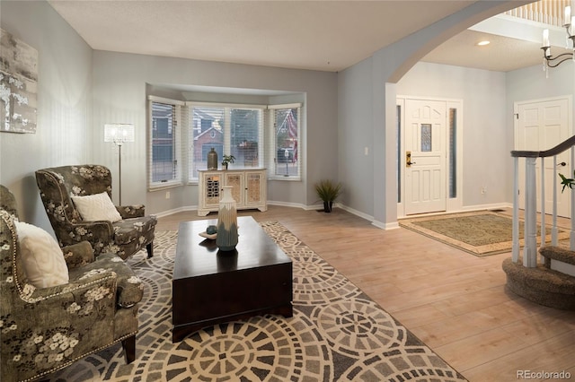 living area with recessed lighting, wood finished floors, arched walkways, and baseboards