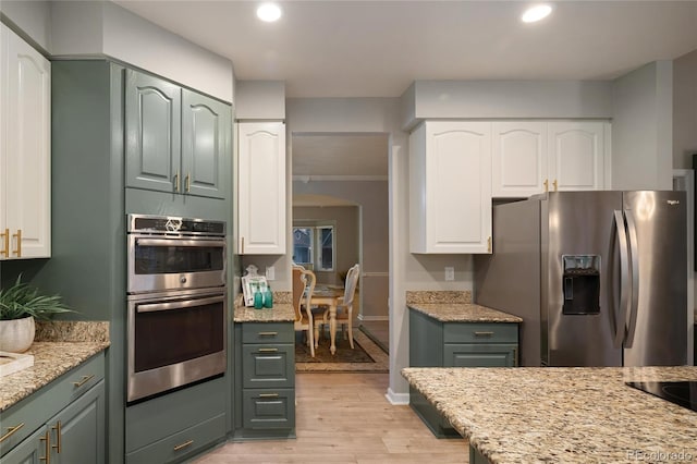 kitchen featuring white cabinets, light stone counters, light wood finished floors, and stainless steel appliances