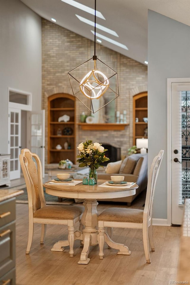 dining space with light wood finished floors, high vaulted ceiling, and an inviting chandelier