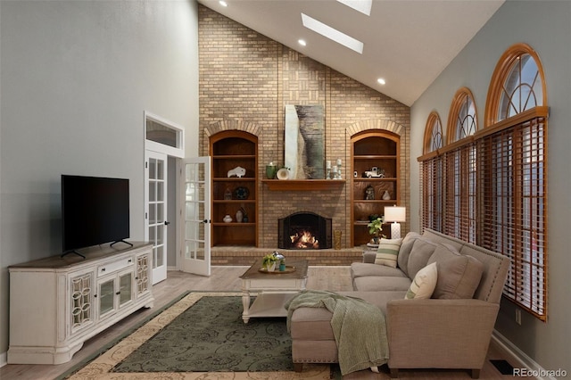 living area featuring a brick fireplace, french doors, a skylight, wood finished floors, and high vaulted ceiling