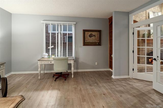 home office with light wood-style flooring, baseboards, and a textured ceiling