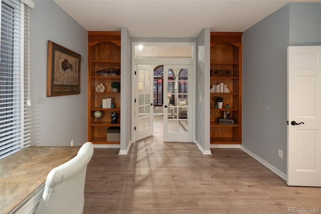 interior space with french doors, baseboards, and light wood finished floors