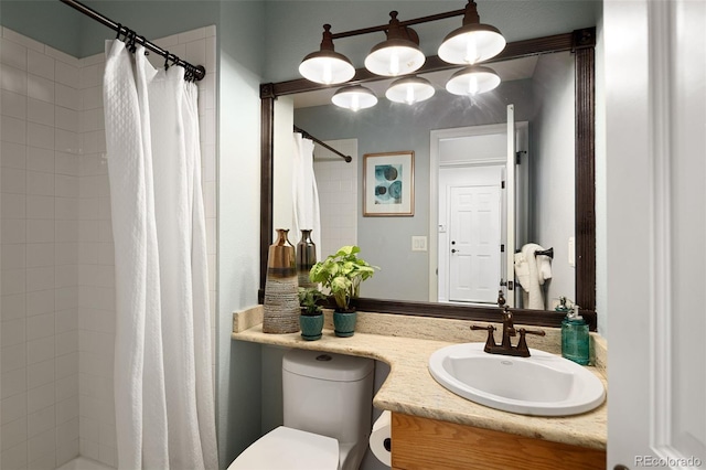 bathroom with vanity, toilet, and tiled shower