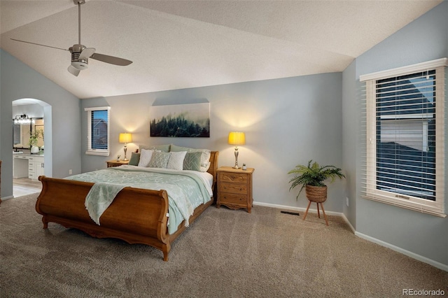 carpeted bedroom featuring baseboards, arched walkways, ceiling fan, vaulted ceiling, and connected bathroom