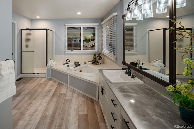 bathroom with a shower stall, a garden tub, recessed lighting, wood finished floors, and vanity