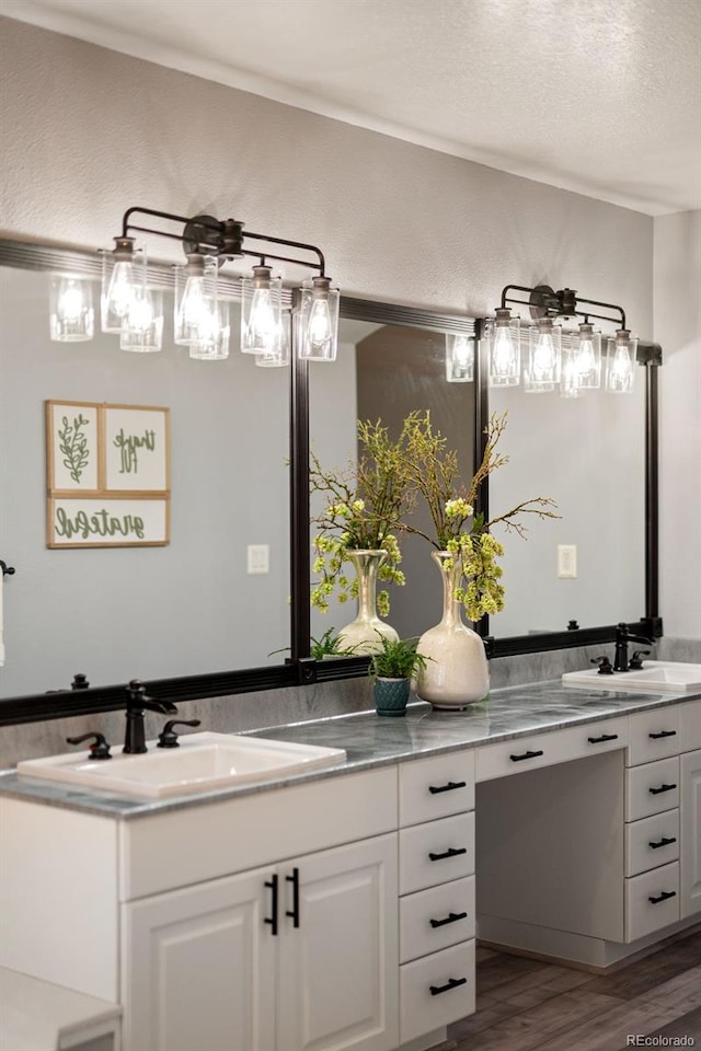 full bathroom with double vanity, a textured ceiling, wood finished floors, and a sink