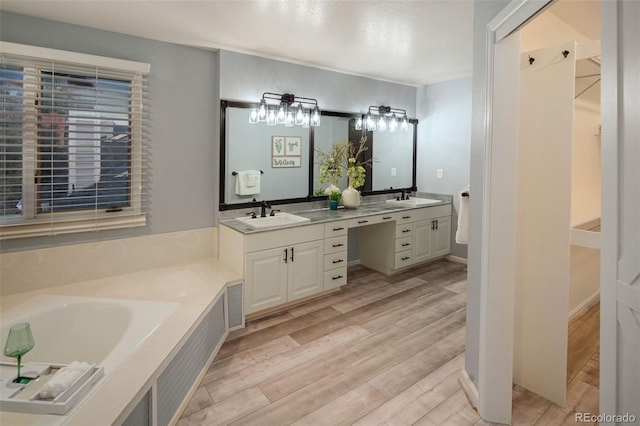 bathroom with double vanity, a bath, wood finished floors, and a sink