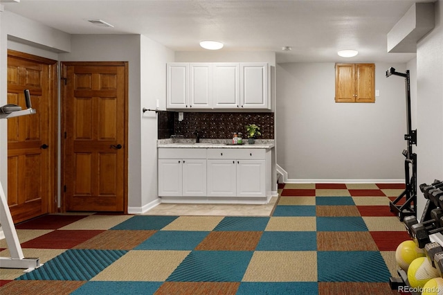 kitchen featuring light countertops, white cabinets, baseboards, and tasteful backsplash