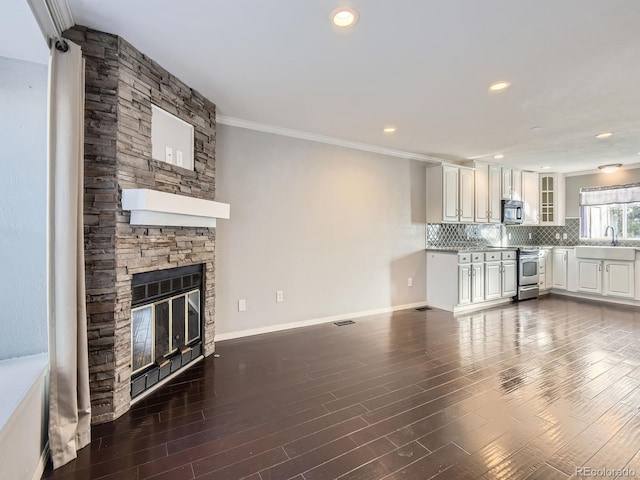 unfurnished living room featuring a stone fireplace, dark hardwood / wood-style flooring, and ornamental molding