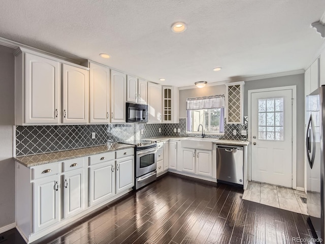 kitchen featuring sink, dark wood-type flooring, appliances with stainless steel finishes, white cabinetry, and light stone countertops