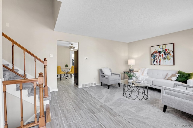 living room with ceiling fan and a textured ceiling