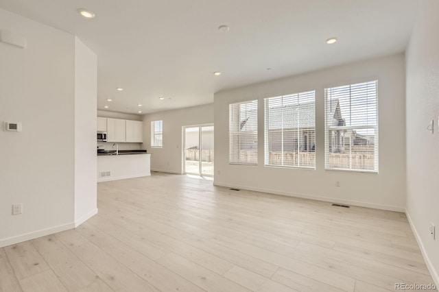 unfurnished living room featuring recessed lighting, light wood-type flooring, and visible vents