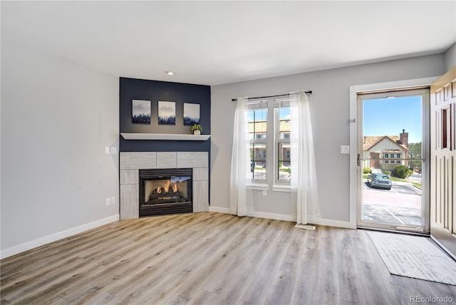 6840 Goldcrest Ct, Colorado Springs, CO 80919 - unfurnished living room with wood finished floors, a tiled fireplace, baseboards, and recessed lighting