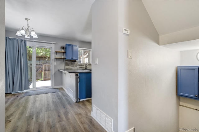 6840 Goldcrest Ct, Colorado Springs, CO 80919 - kitchen featuring blue cabinets, a chandelier, wood finished floors, tasteful backsplash, and baseboards