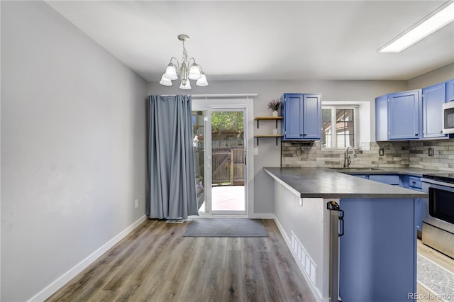 6840 Goldcrest Ct, Colorado Springs, CO 80919 - kitchen featuring stainless steel appliances, blue cabinets, dark countertops, a peninsula, and a chandelier