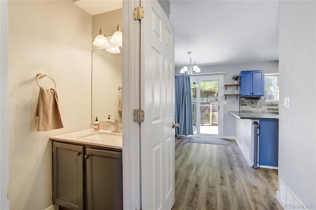6840 Goldcrest Ct, Colorado Springs, CO 80919 - bathroom with a chandelier, vanity, wood finished floors, backsplash, and baseboards