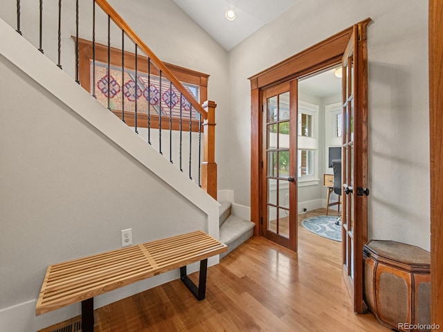 entrance foyer with french doors, light hardwood / wood-style floors, and lofted ceiling