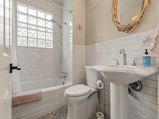 bathroom featuring shower / bathtub combination with curtain, tile walls, and toilet