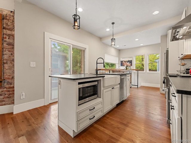 kitchen with pendant lighting, plenty of natural light, a kitchen island with sink, and stainless steel appliances