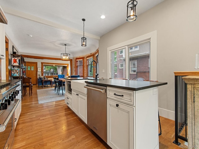 kitchen featuring hanging light fixtures, stainless steel appliances, an island with sink, white cabinets, and light wood-type flooring