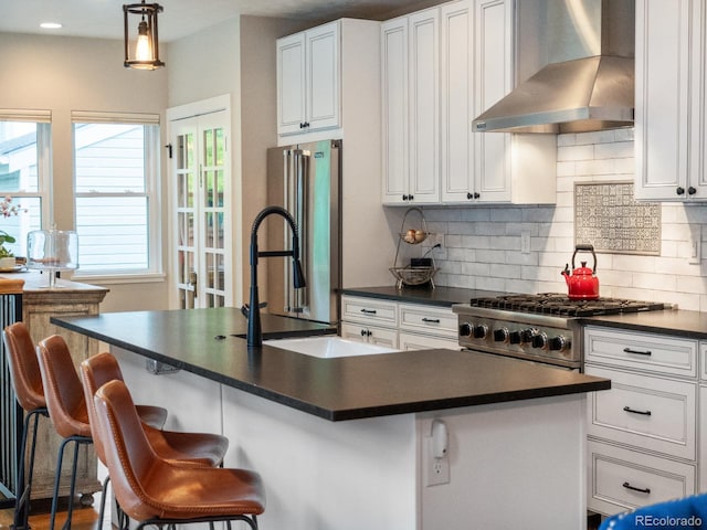 kitchen with white cabinetry, wall chimney range hood, stainless steel appliances, and a breakfast bar area