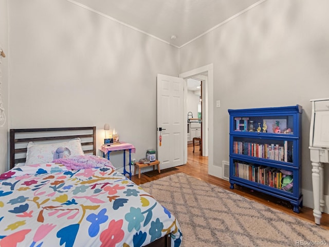 bedroom with crown molding and hardwood / wood-style floors