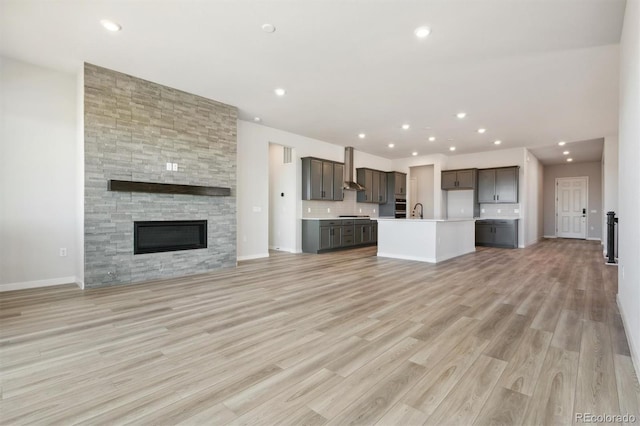 unfurnished living room with light wood finished floors, a fireplace, baseboards, and recessed lighting