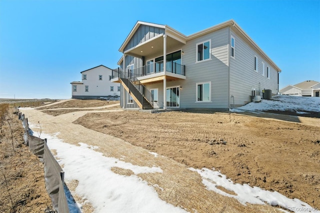 back of property with stairs, central AC unit, and board and batten siding