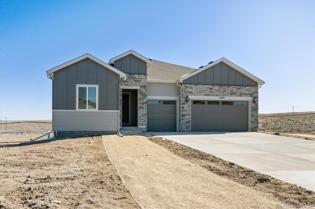 view of front facade with a garage, concrete driveway, board and batten siding, and stone siding