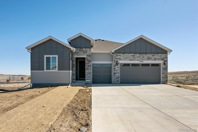 view of front facade with a garage, concrete driveway, board and batten siding, and stone siding